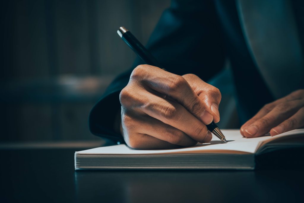 Closeup of man writing in notebook for project